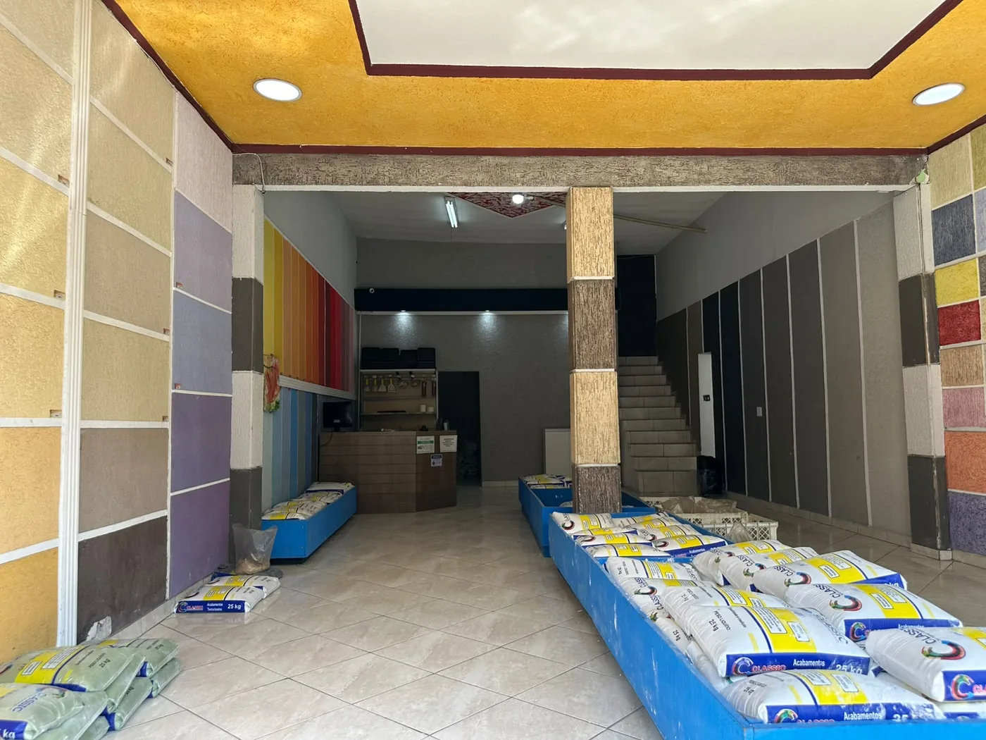 Interior da loja da Vila Albertina, com painéis de textura nas paredes e sacos de material prontos para retirada