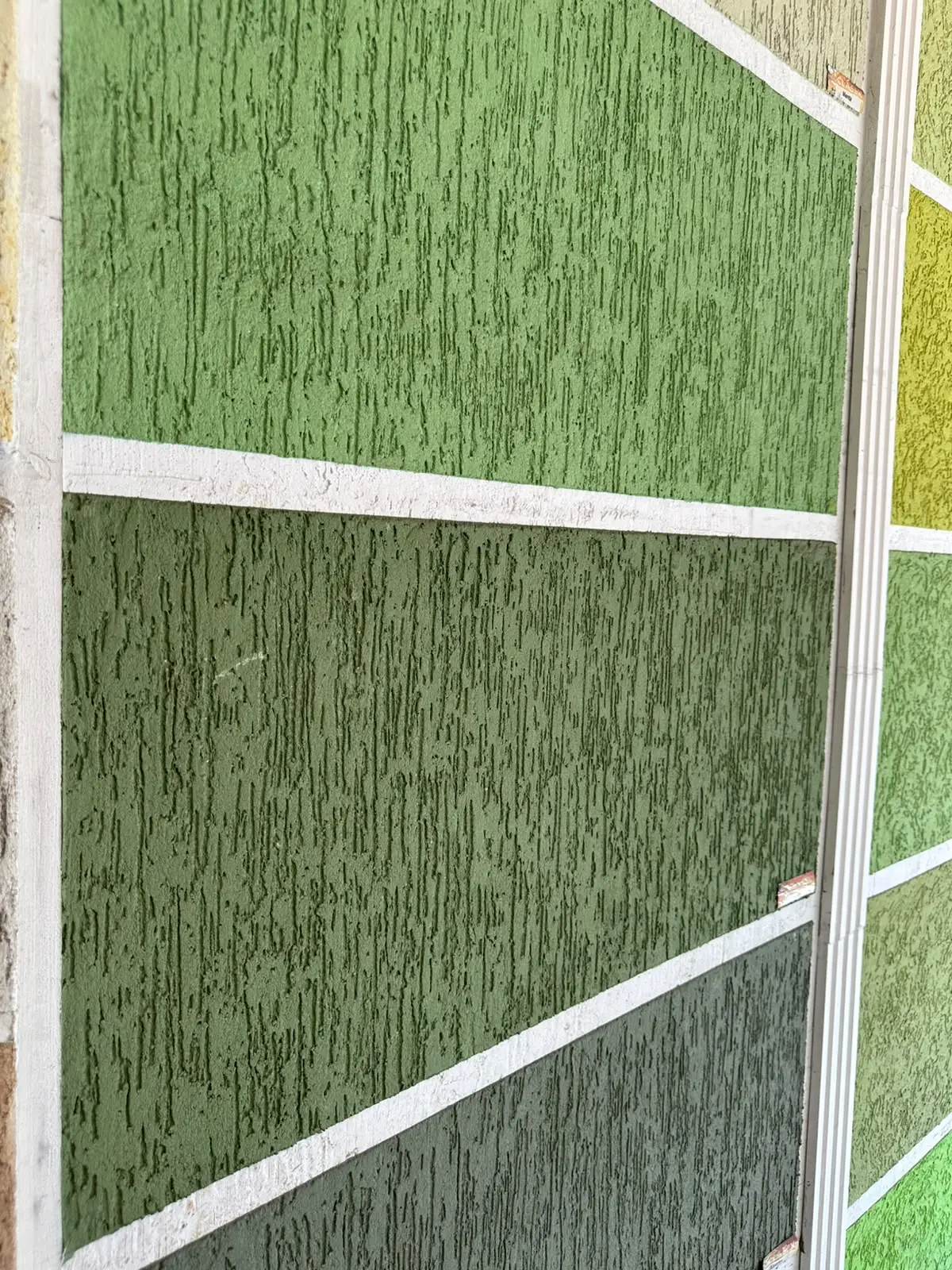 Painéis de grafiato rústico em tons de verde, com o risco vertical marcado no relevo