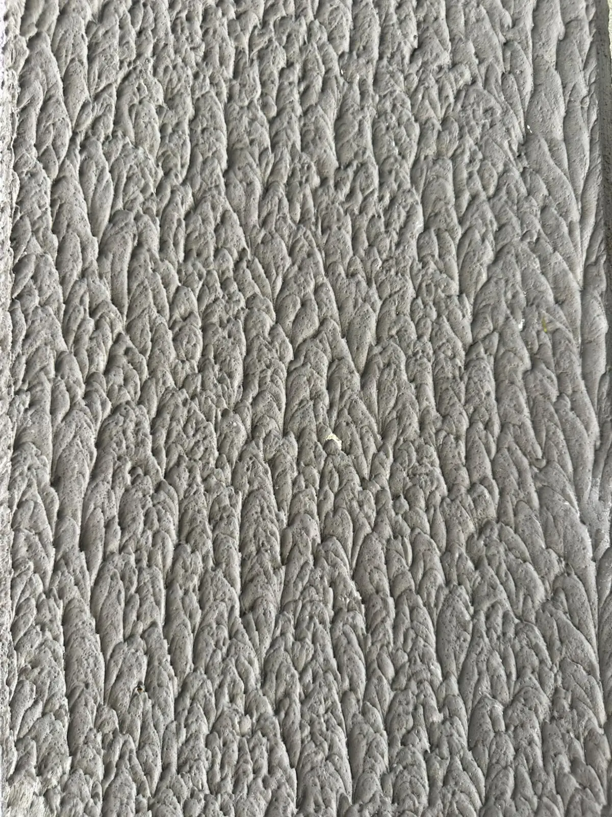 Parede com textura design cinza, relevo alto e desenho em escamas repetido por toda a superfície